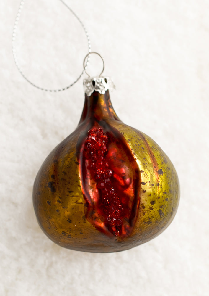 A glass holiday ornament of a fig with slice out of it.