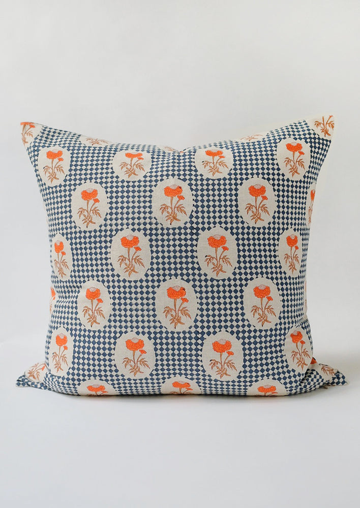 A block printed square pillow with navy diamond checker and orange floral pattern.