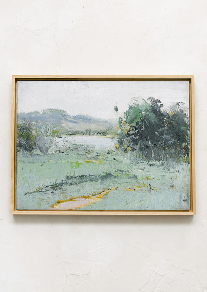 A framed original painting of a cool-colored lakeside landscape setting.