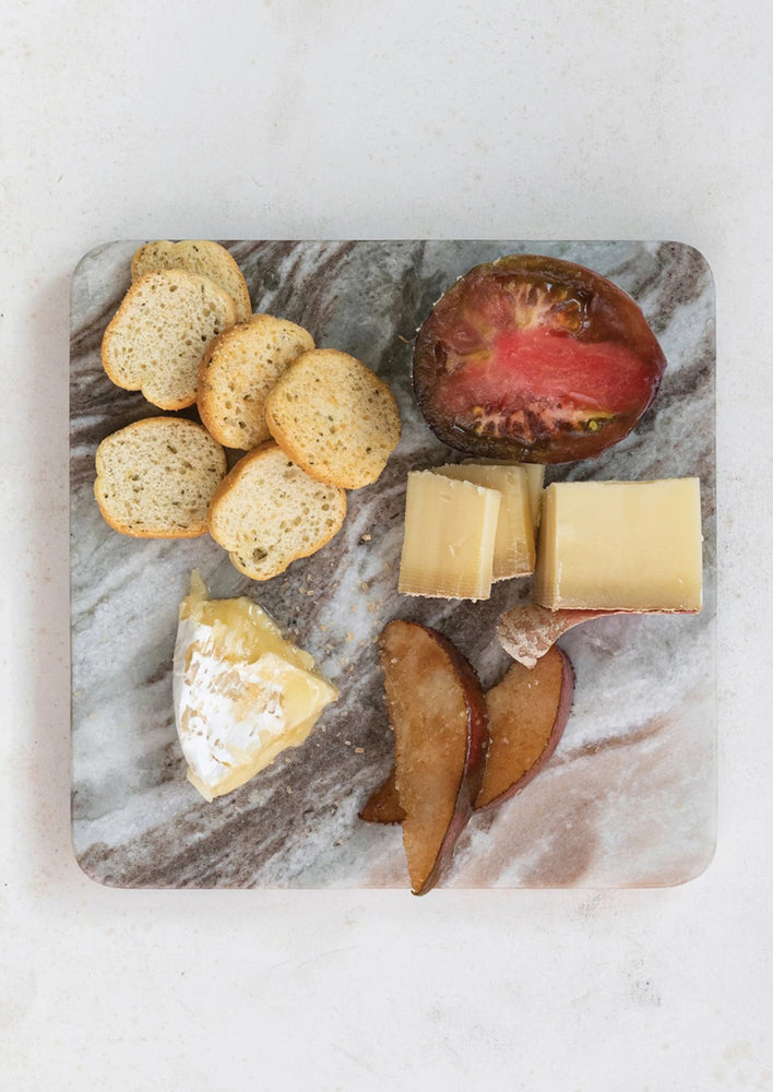 A marble trivet holding cheese and crackers.