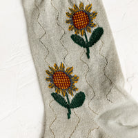 3: A pair of seafoam colored socks with sunflower pattern.