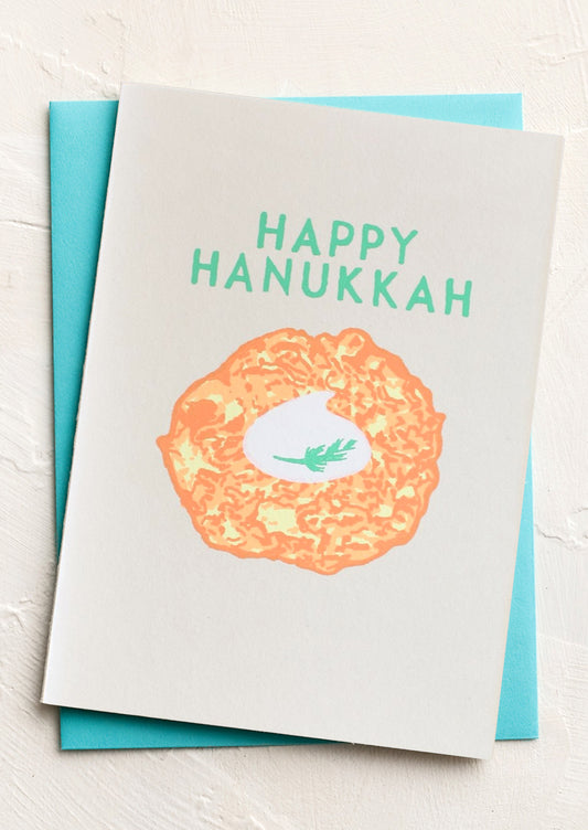 Card with 'Happy Hanukkah' text and a latke illustration on a white background
