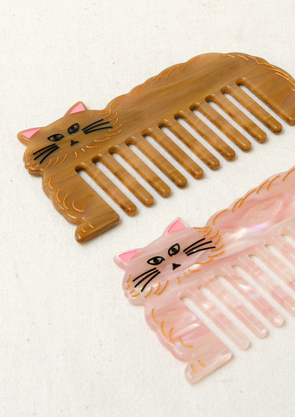 A pink and brown hair combs in the shape of a cat.