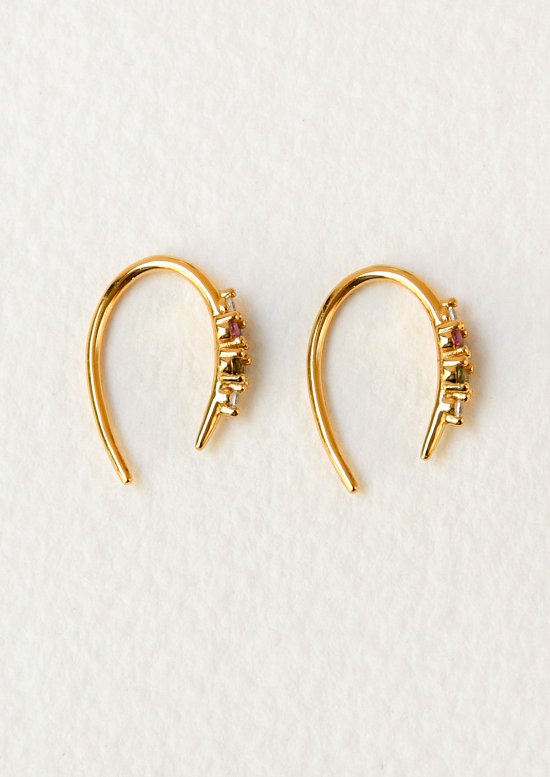 A pair of gold open hoop earrings with various colored glass stones adorned on the front.