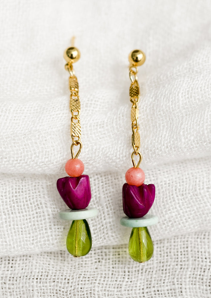 A pair of drop earrings with gold chain and beads.