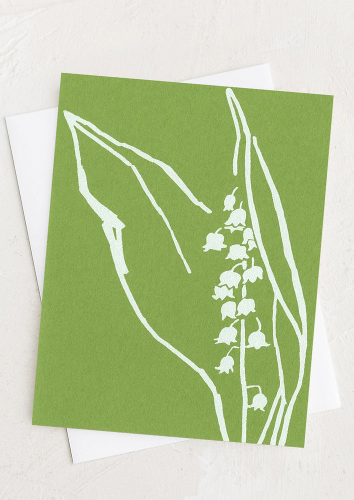 A green greeting card with silk screened lily of the valley in white.