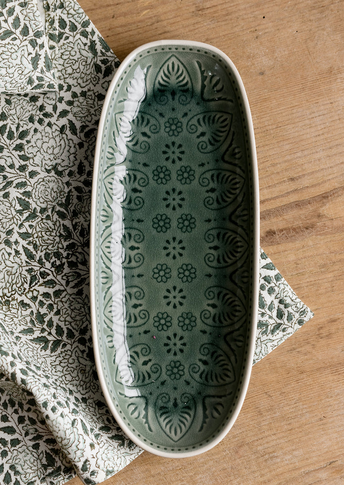 An oblong, curved platter in glossy green glaze with Polish inspired pattern.