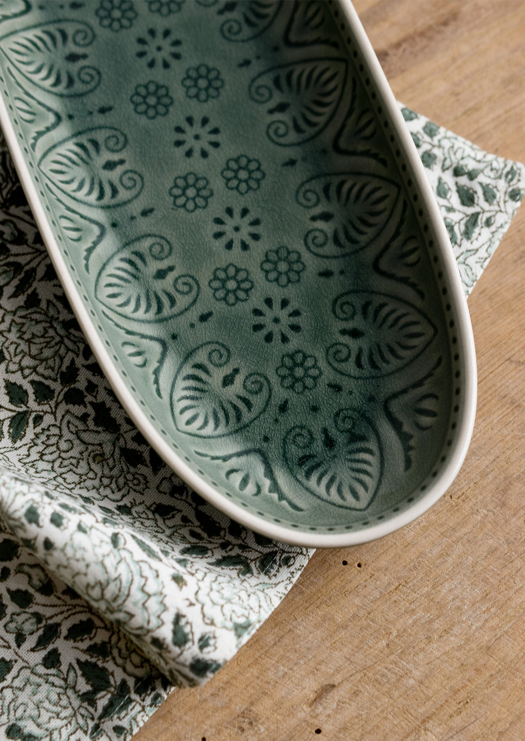 3: An oblong, curved platter in glossy green glaze with Polish inspired pattern.