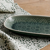 2: An oblong, curved platter in glossy green glaze with Polish inspired pattern.