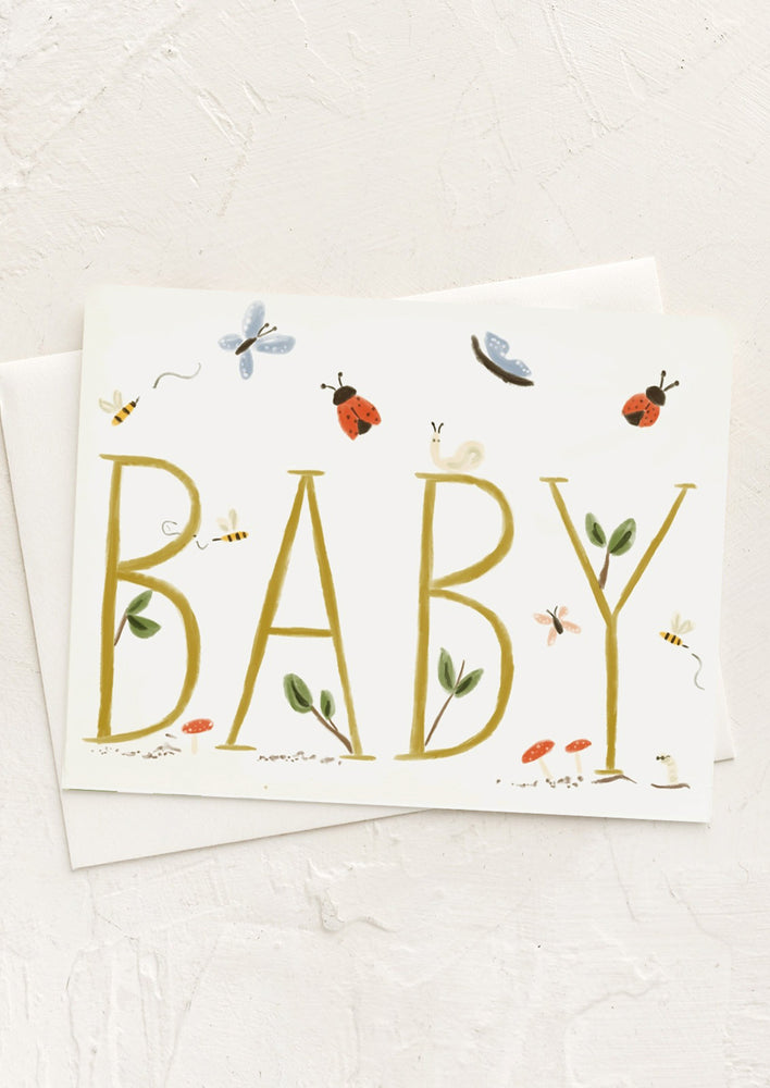 A greeting card with small cute bug print reading "BABY" in large text.