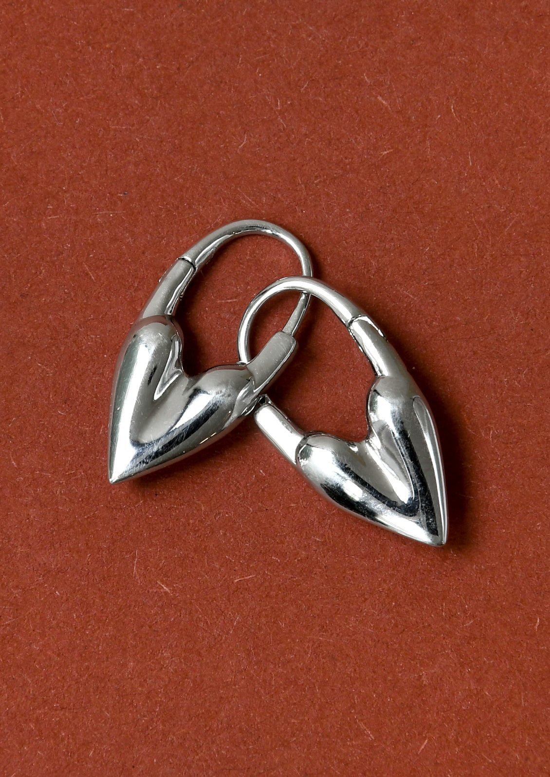 A pair of silver hoop earrings in the shape of a heart.