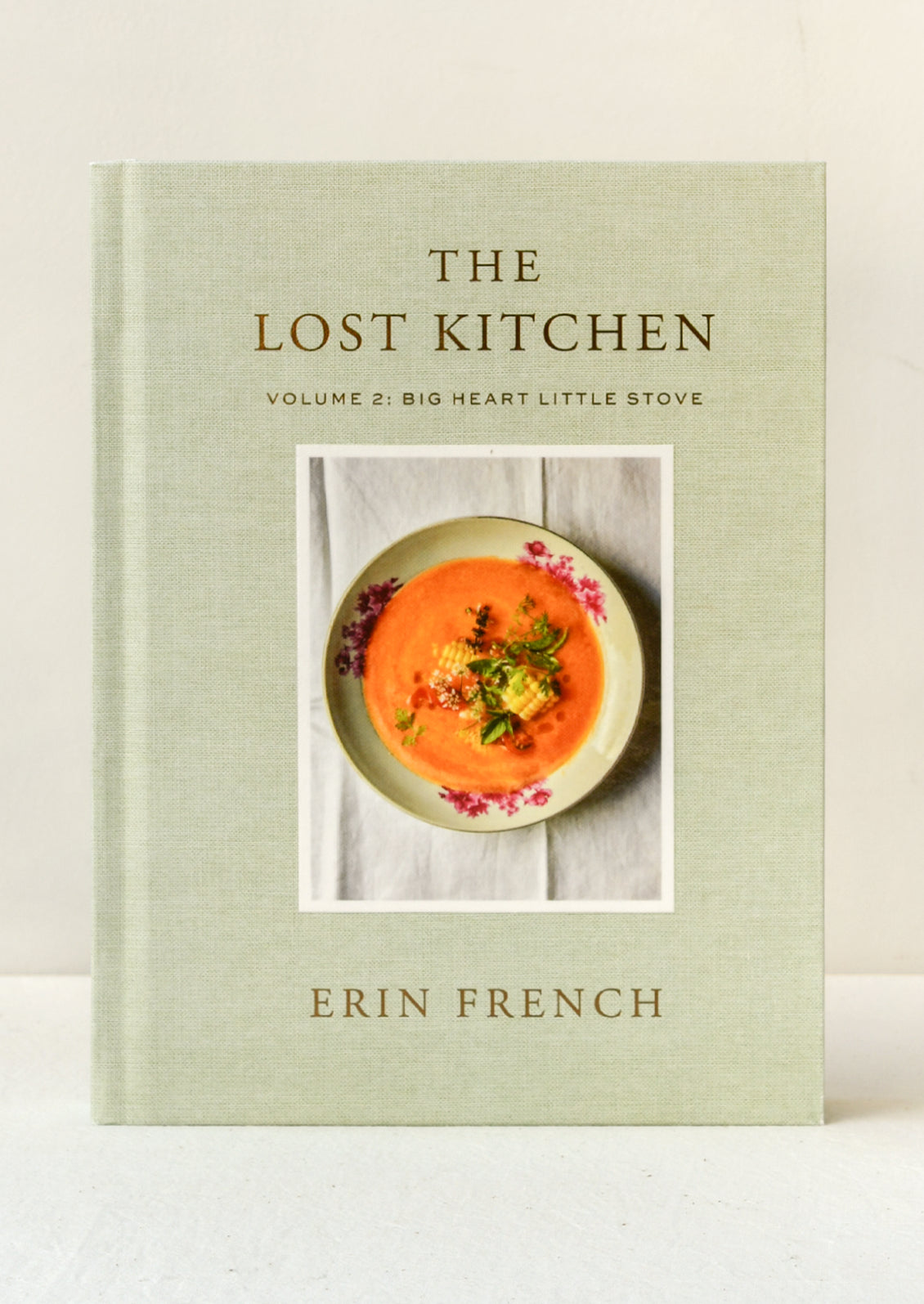 A book titled "The Lost Kitchen Volume 2: Big Heart Little Stove" by Erin French standing upright on a table.