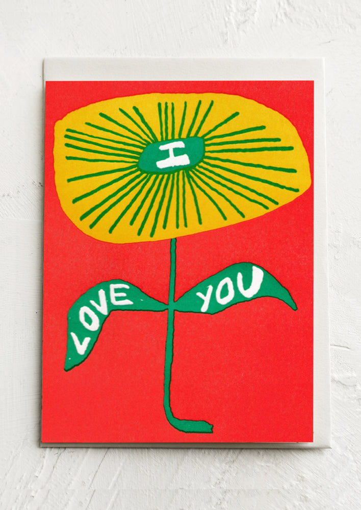 A red card with yellow flower reading "I love you".