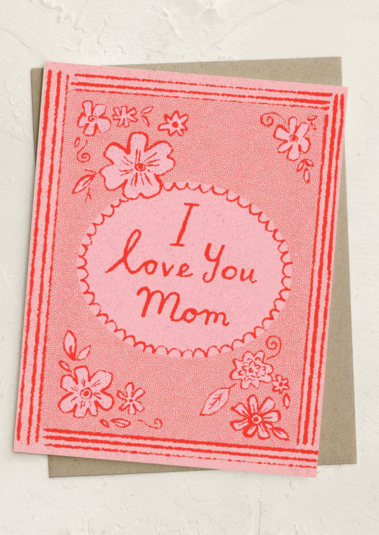 Greeting card with 'I love you Mom' text on a pink background with floral designs.