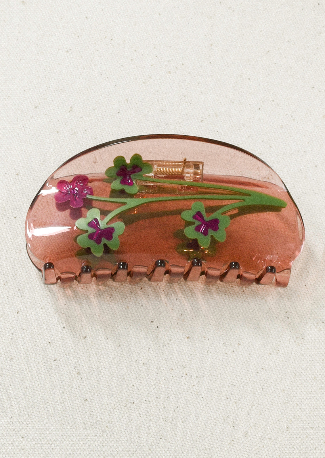 A transparent hair claw with green and purple clovers.