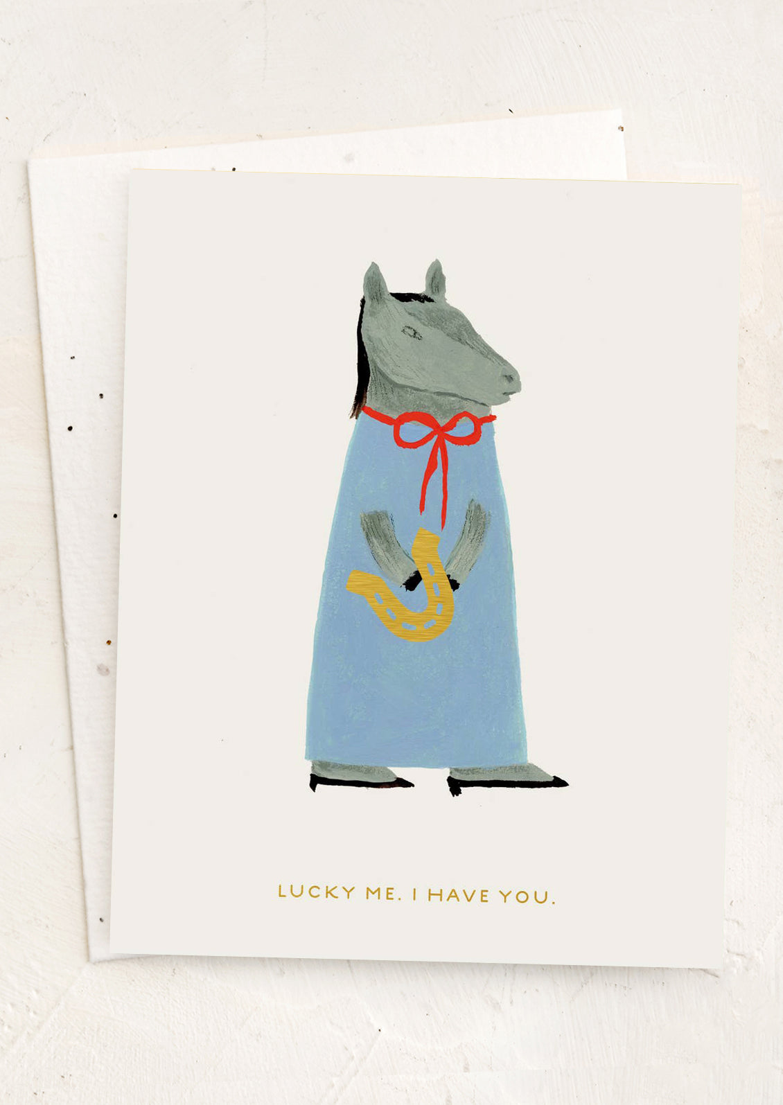 Card with a horse illustration wearing a blue dress with a red bow and yellow horseshoe, text 'Lucky me, I have you' on a white background.