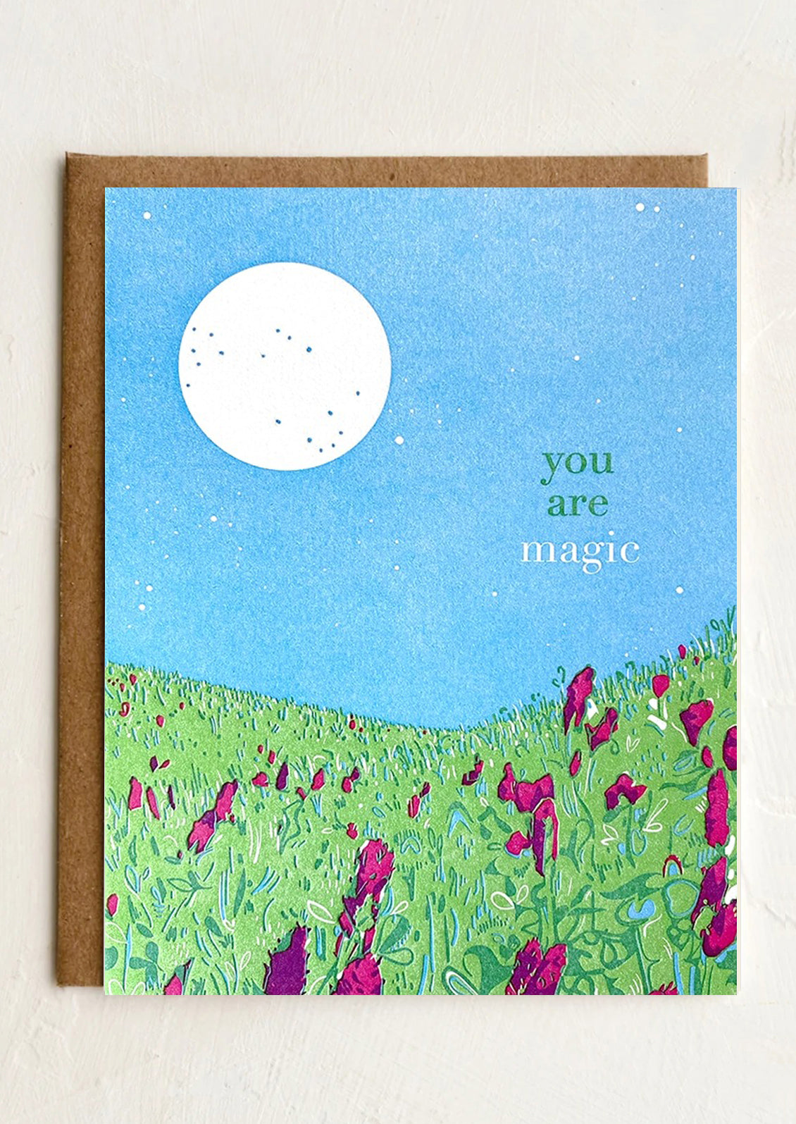 A greeting card with image of a moon over a meadow, text reads "You are magic".