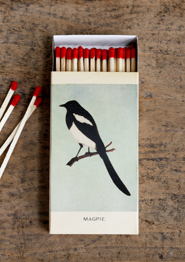 A swallow and magpie bird printed matchbox with red-tipped long matches.