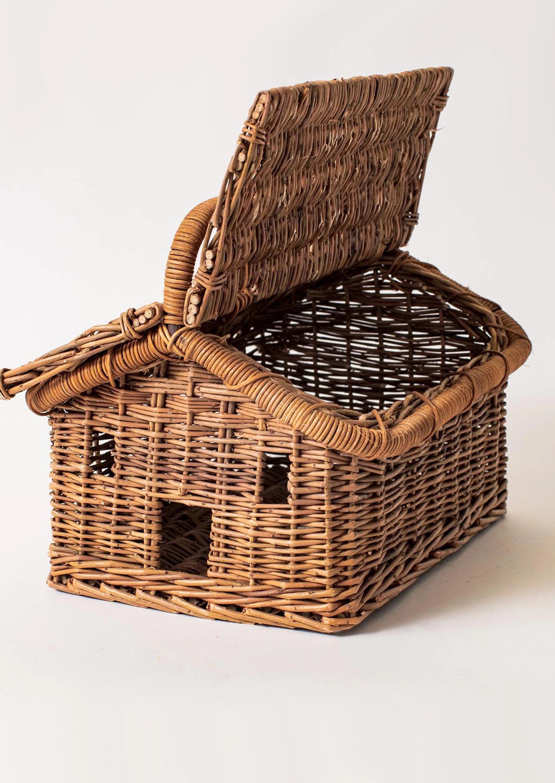 A small brown wicker basket shaped like a house with an open hinged lid.