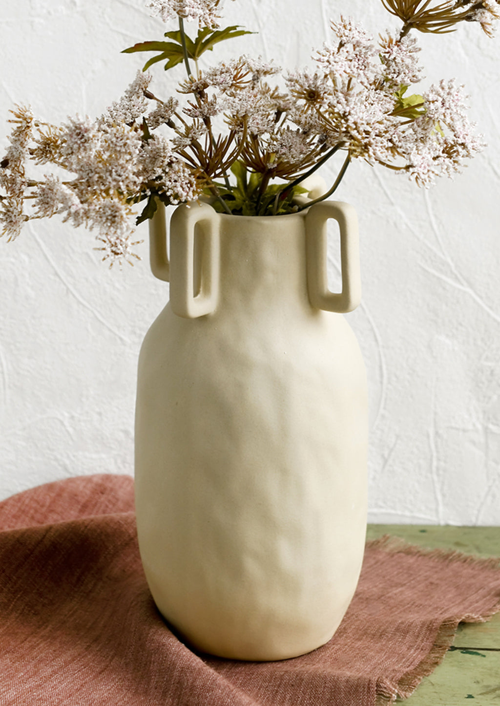 1: A sand color vase in matte ceramic with decorative square handle detail around mouth.