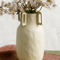 1: A sand color vase in matte ceramic with decorative square handle detail around mouth.