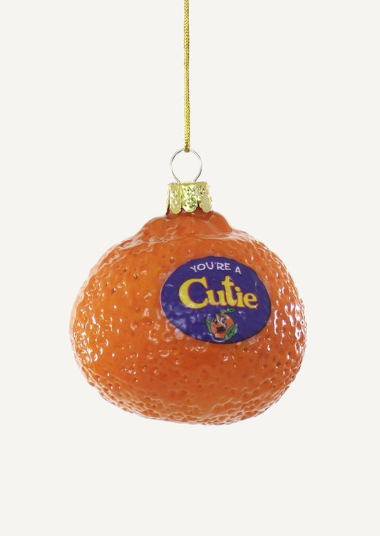 A glass ornament of a mandarin orange with produce sticker reading "You're a Cutie".