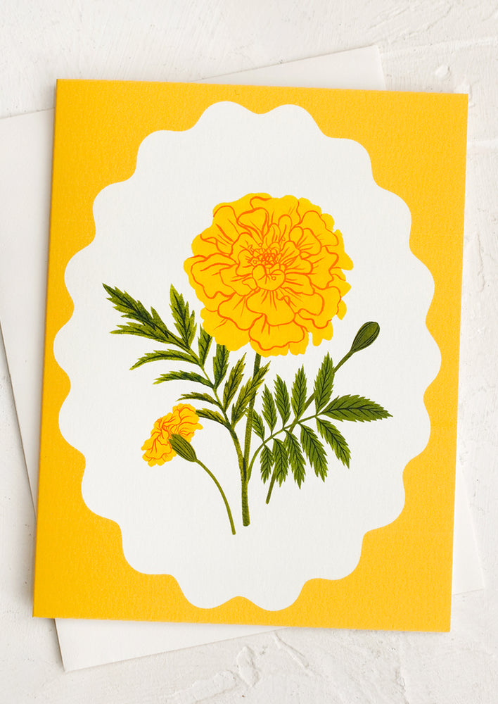 A yellow card with white scalloped frame showing marigold flower.