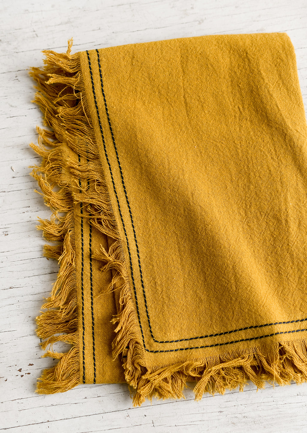 Mustard: A mustard tea towel with navy stitching.