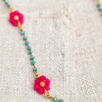 2: A beaded necklace with turquoise beads and pink flowers.