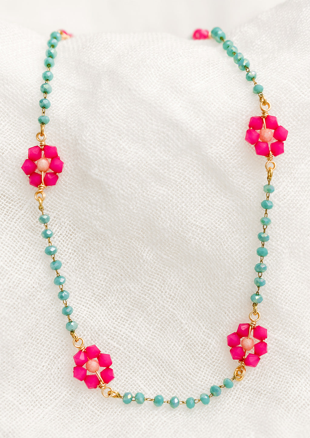 1: A beaded necklace with turquoise beads and pink flowers.