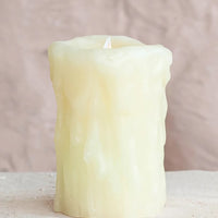 1: A flameless electronic pillar candle in natural color with drippy appearance.