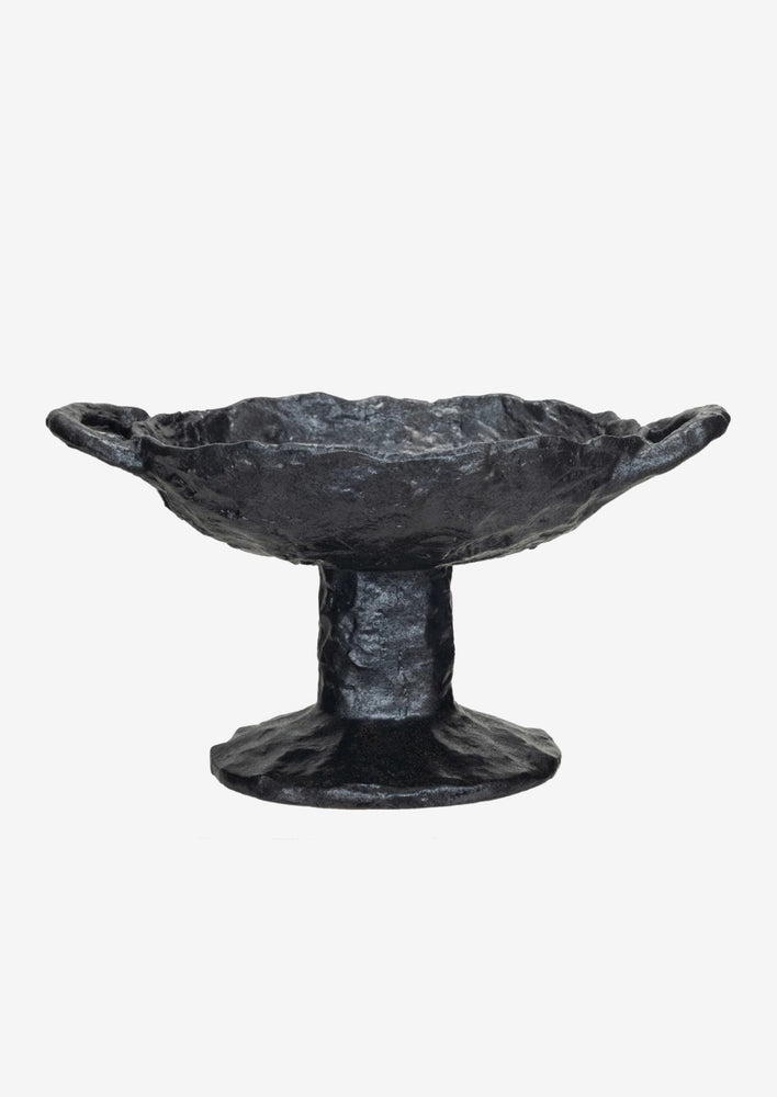 A footed ceramic bowl  in black with side handles at top.