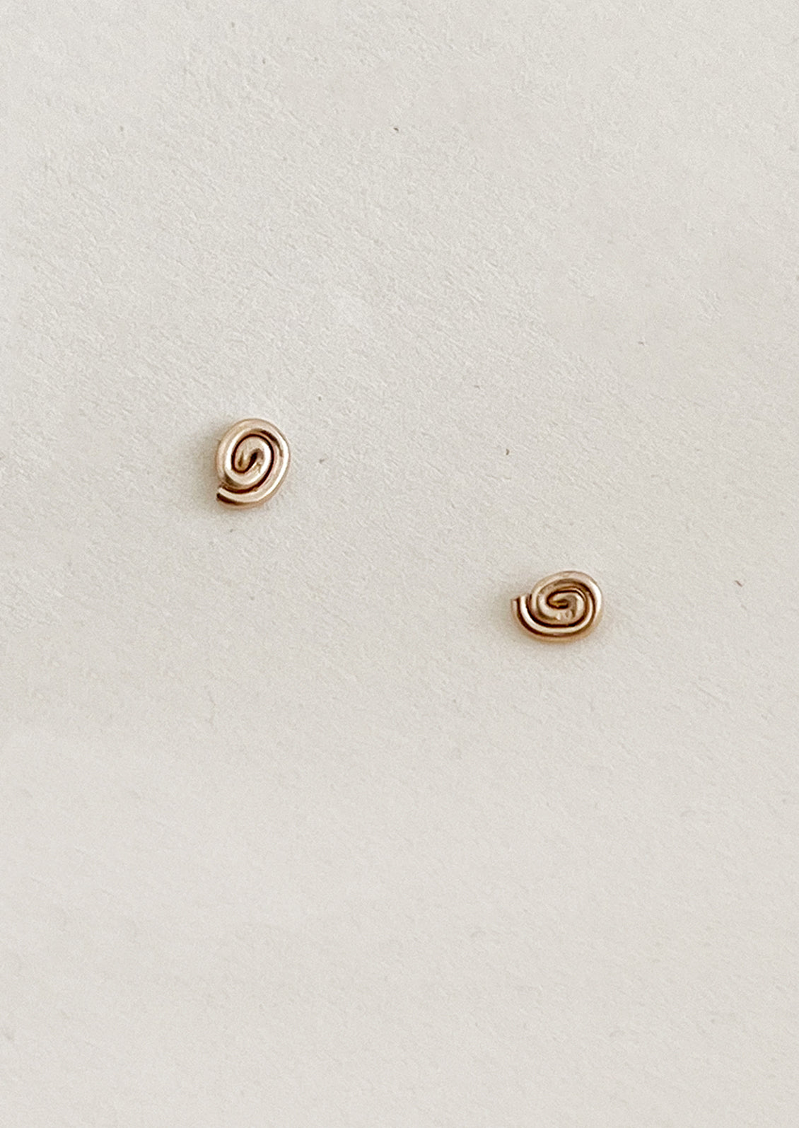 Pair of gold spiral earrings on a light beige background