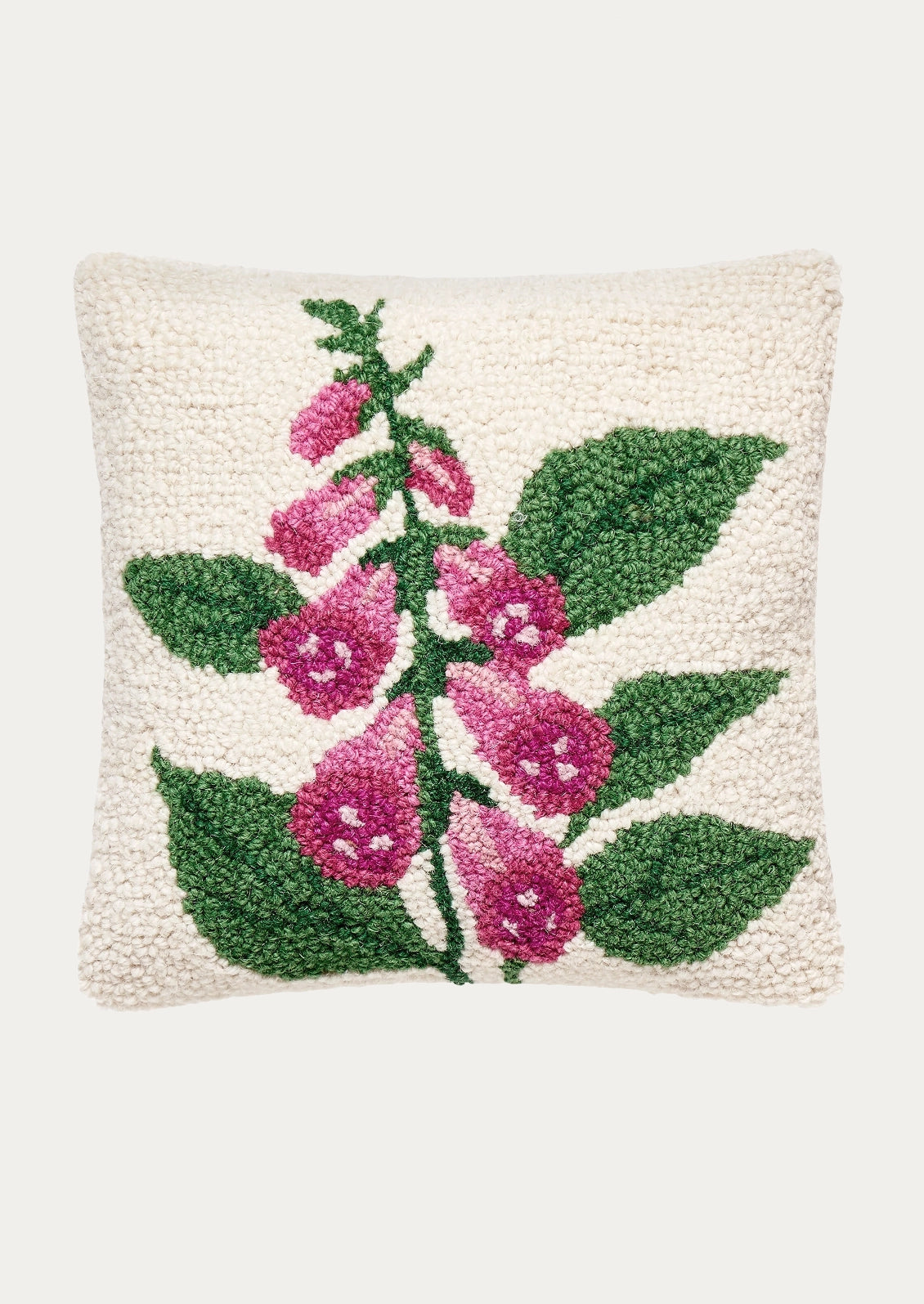 A square textured throw pillow featuring a hand-hooked floral design of pink foxglove flowers and green leaves on an off-white background, shown against a light gray studio backdrop.