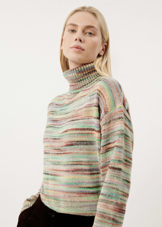 A woman wearing a turtleneck sweater in multicolor spacedye knit.