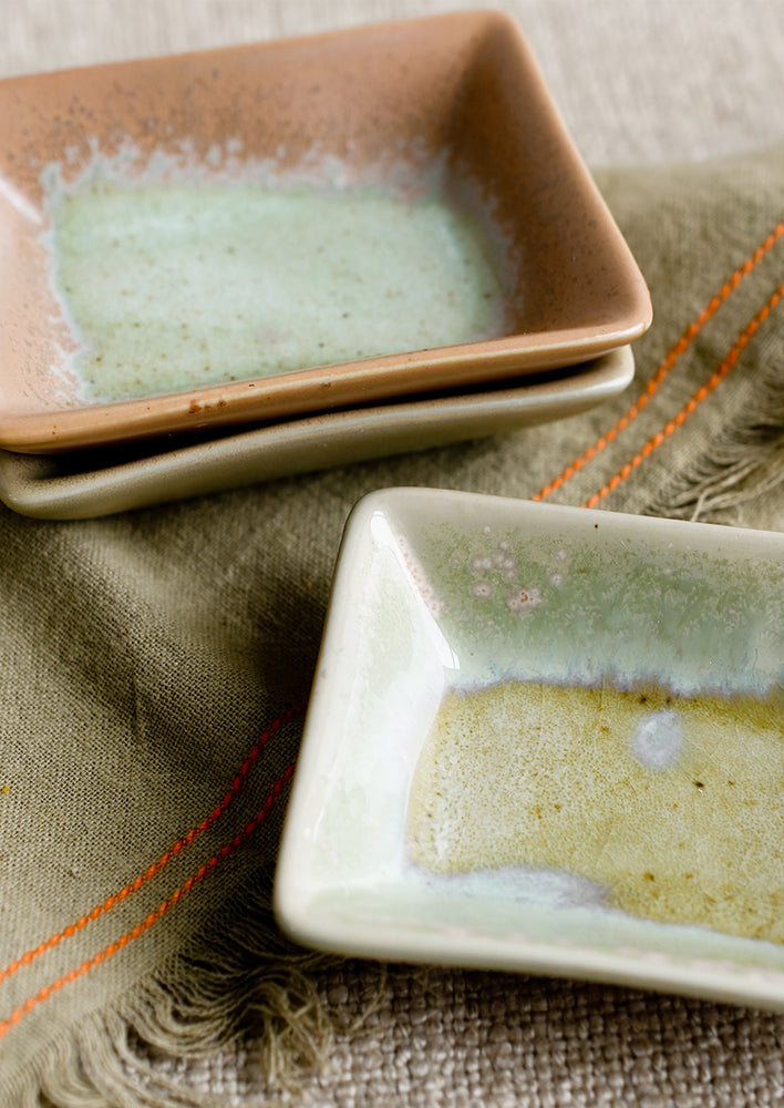 Rectangular ceramic sauce dishes in turquoise, green and brown varied glazes.