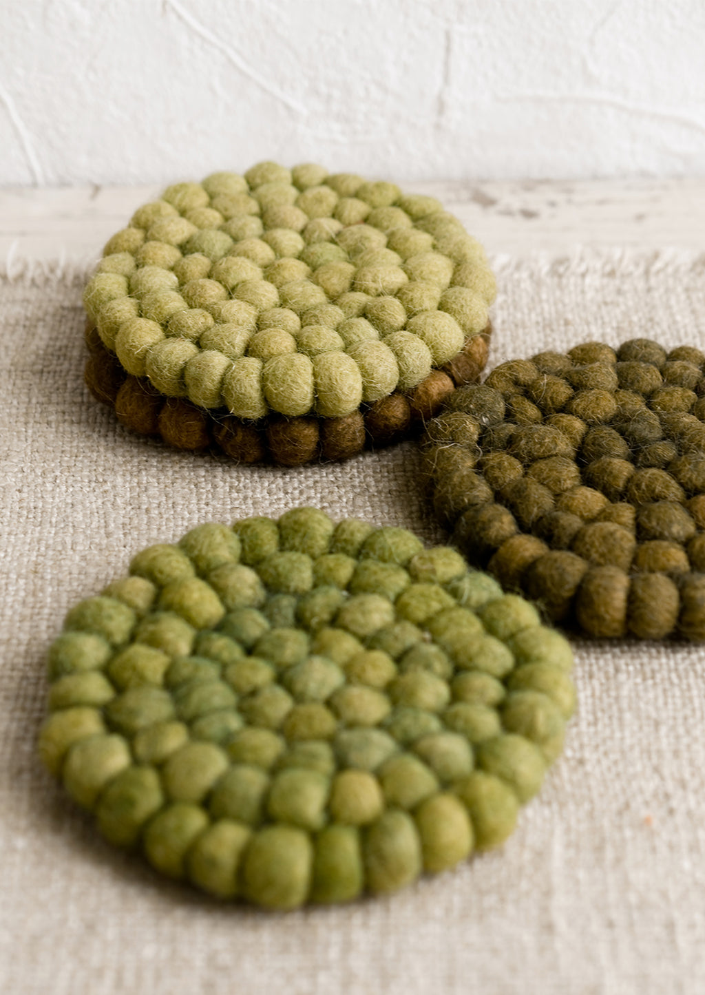 2: A set of felted ball coasters in mixed tones of green.