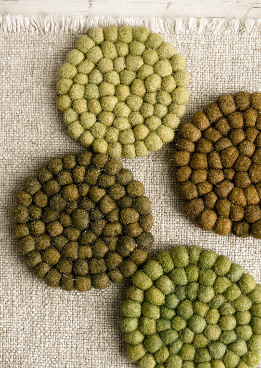 4: A set of felted ball coasters in mixed tones of green.