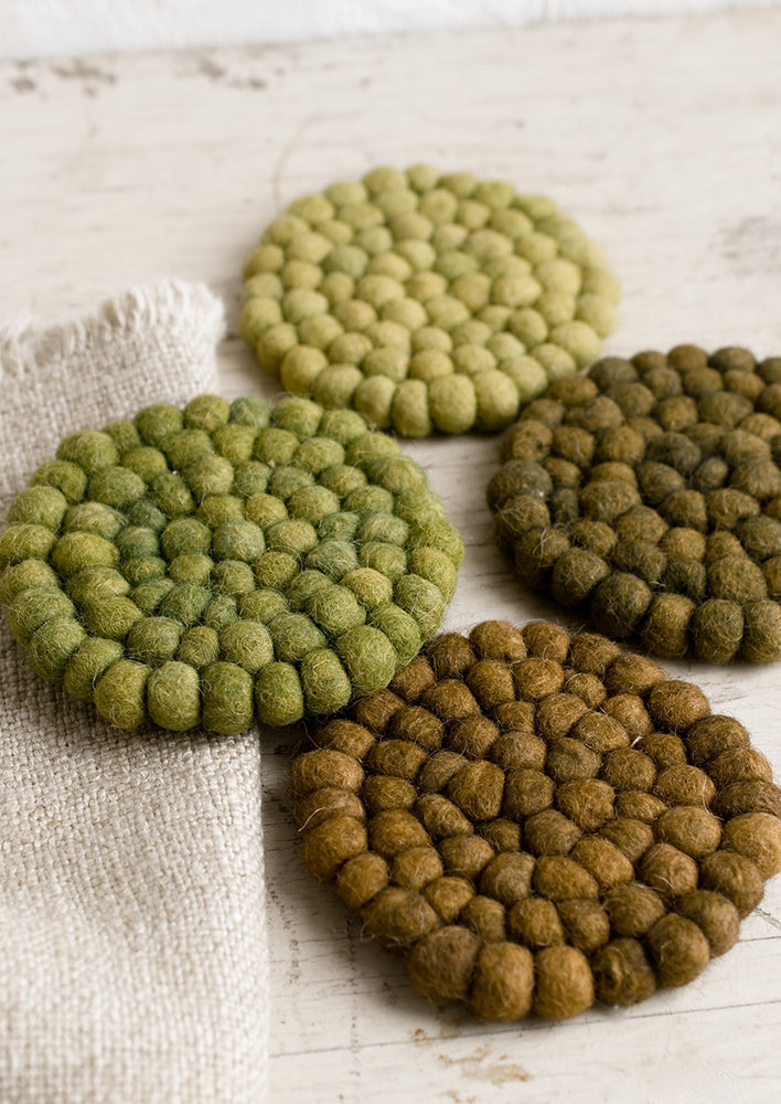 A set of felted ball coasters in mixed tones of green.
