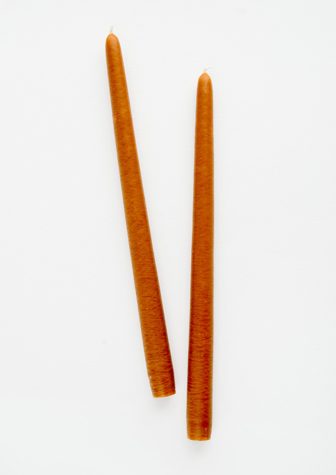 A pair of taper candles in cinnamon color.