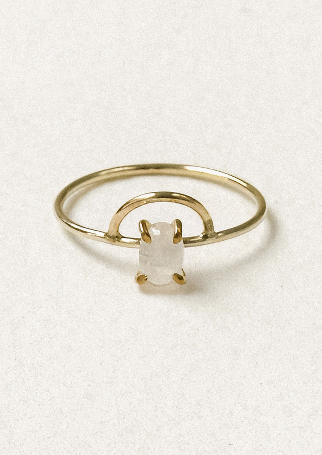 A gold ring with an arch design and an oval moonstone in a prong setting. 