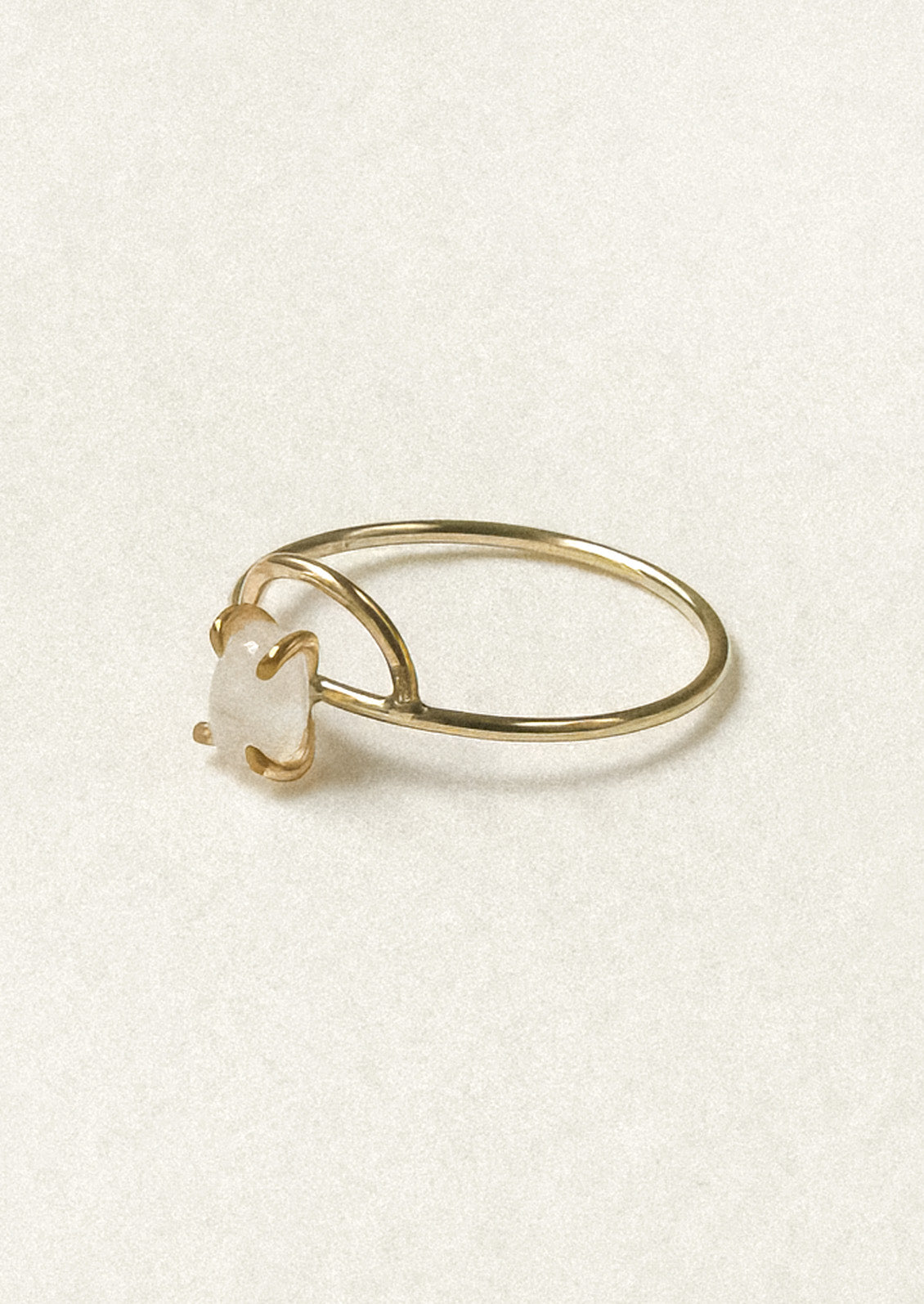 Side view of a gold ring with an arch design and an oval moonstone in a prong setting. 