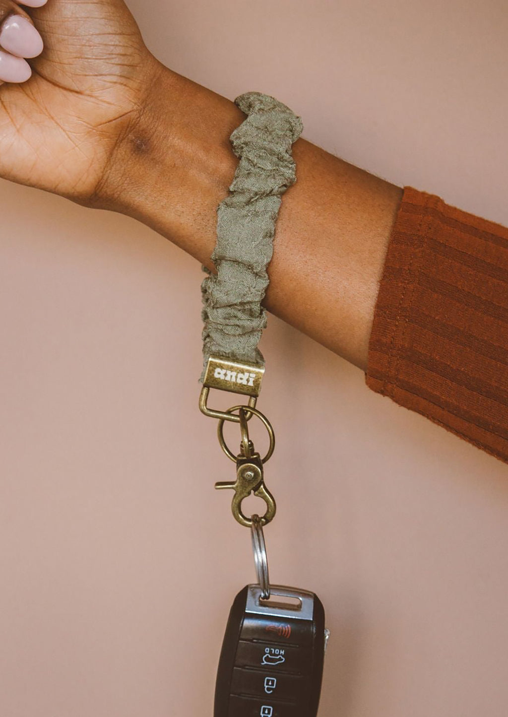 Moss Crinkle: A moss crinkle scrunchie wristlet keychain around a woman's wrist.