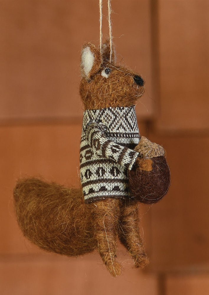 1: A felted holiday ornament of brown squirrel holding acorn.
