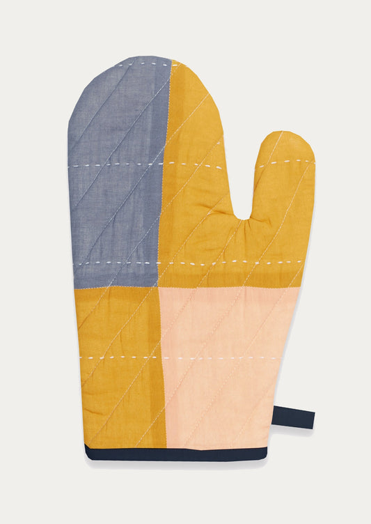 Multicolored quilted oven mitt in blue, mustard, navy and peach.