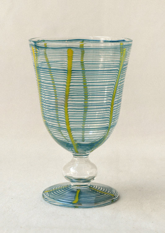 Decorative glass goblet with blue and green stripes on a light background