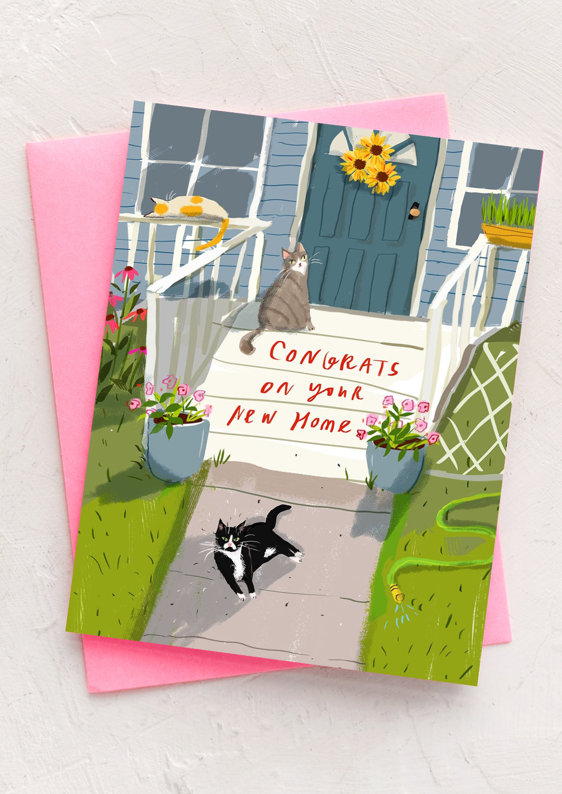 An illustrated greeting card with cats sitting on stoop, text reads "Congrats on your new home".
