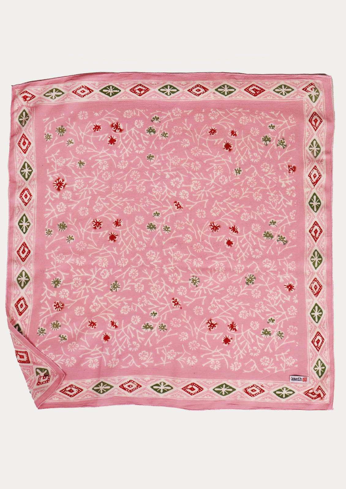 A square cotton bandana in candy pink color with red and green floral pattern and geometric border.