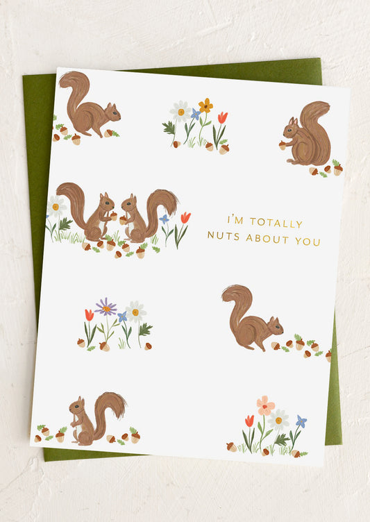 Greeting card with squirrels and flowers and text 'I'm totally nuts about you' on a white background.