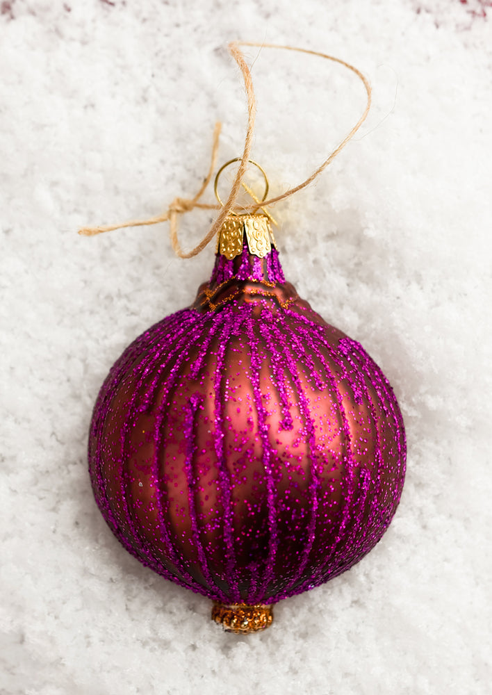 A glass holiday ornament of a sliced red onion.